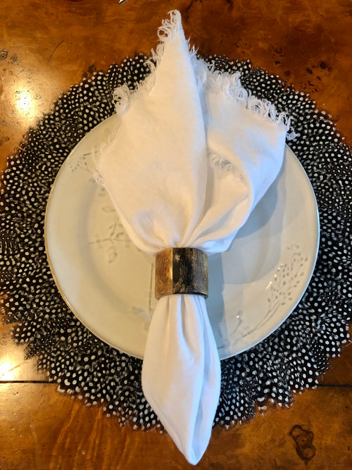 Natural Guinea feather placemat styled beneath a place setting